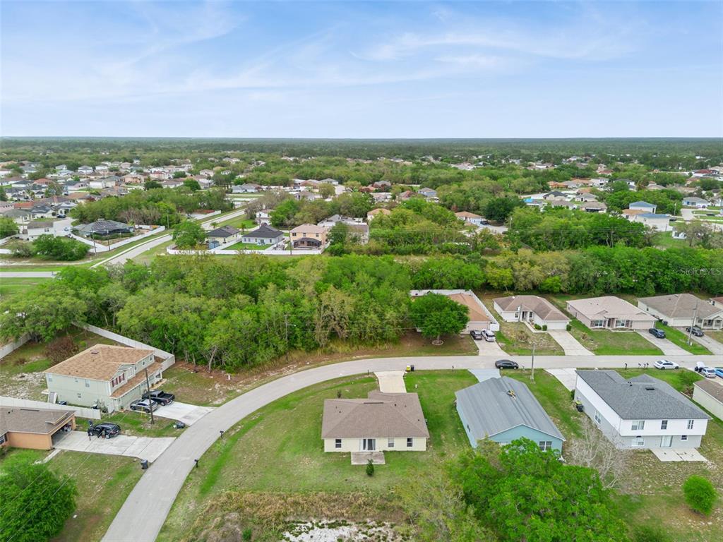 An aerial view shows a suburban neighborhood with several single-family homes and wooded areas — 1923 MICHIGAN COURT, KISSIMMEE, FL