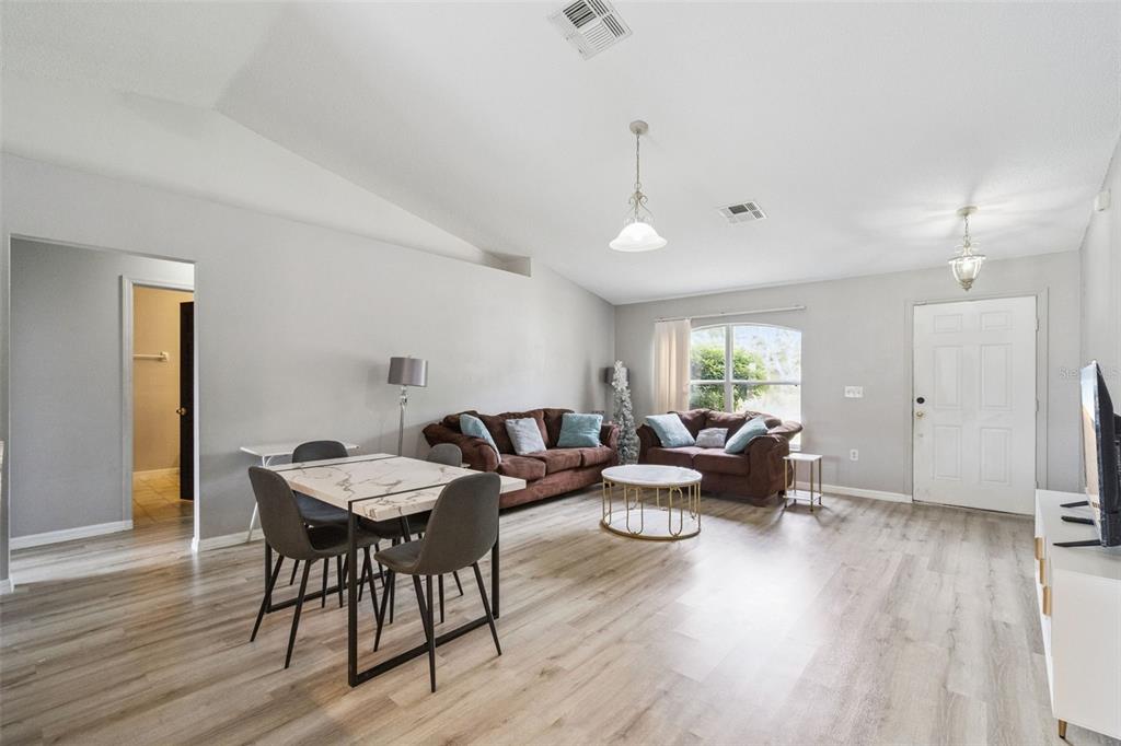 A living room features light wood-look flooring, two brown sofas, and a small dining area — 1923 MICHIGAN COURT, KISSIMMEE, FL