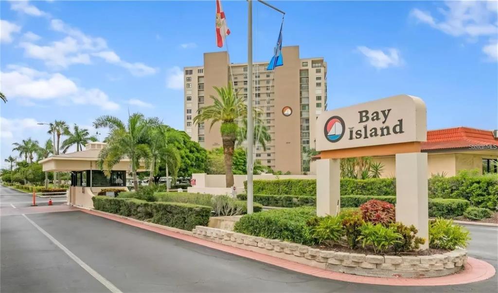 The entrance to the Bay Island community features a gated guardhouse and a prominent sign — 7400 SUN ISLAND DRIVE S UNIT 412, SOUTH PASADENA, FL