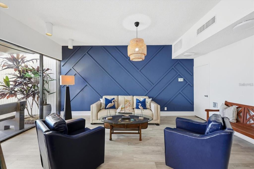 A living room features a blue accent wall with geometric molding and two leather chairs — 7400 SUN ISLAND DRIVE S UNIT 412, SOUTH PASADENA, FL