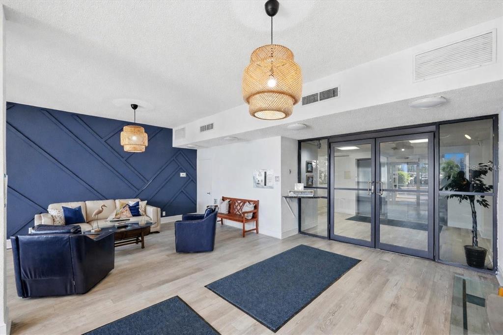 A lobby features a blue accent wall with geometric molding, seating, and two woven pendant lights — 7400 SUN ISLAND DRIVE S UNIT 412, SOUTH PASADENA, FL