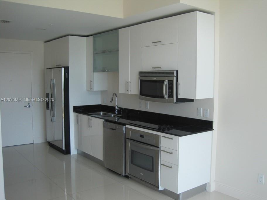 A modern kitchen features white cabinets, stainless steel appliances, and black countertops — 60 SW 13th St # 4610, Miami FL 33130, MIAMI, FL