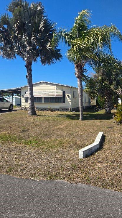 A light-colored mobile home sits on a grassy lot with two tall palm trees — 854 CALLE MENUDA, ENGLEWOOD, FL