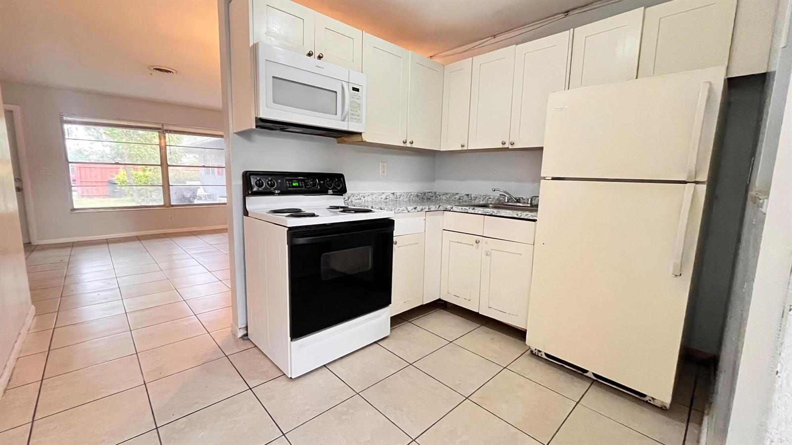 A kitchen features white cabinets, a white stove, a microwave, and a white refrigerator — 919 S G Street, FL 33460, FL