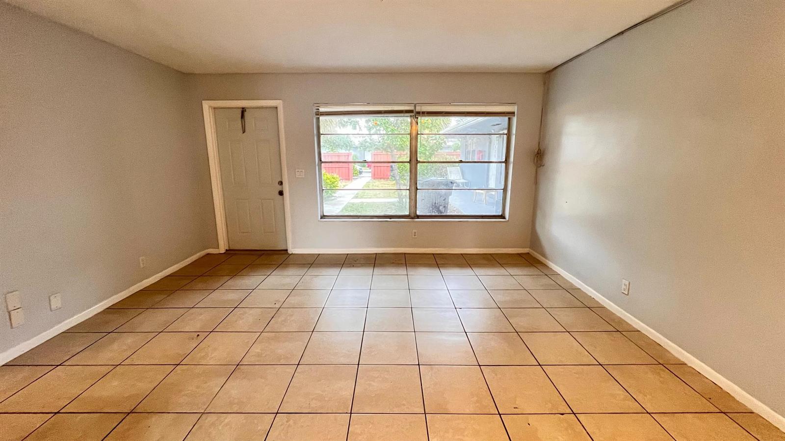 An empty room with light gray walls, tan tile flooring, and a large window — 919 S G Street, FL 33460, FL