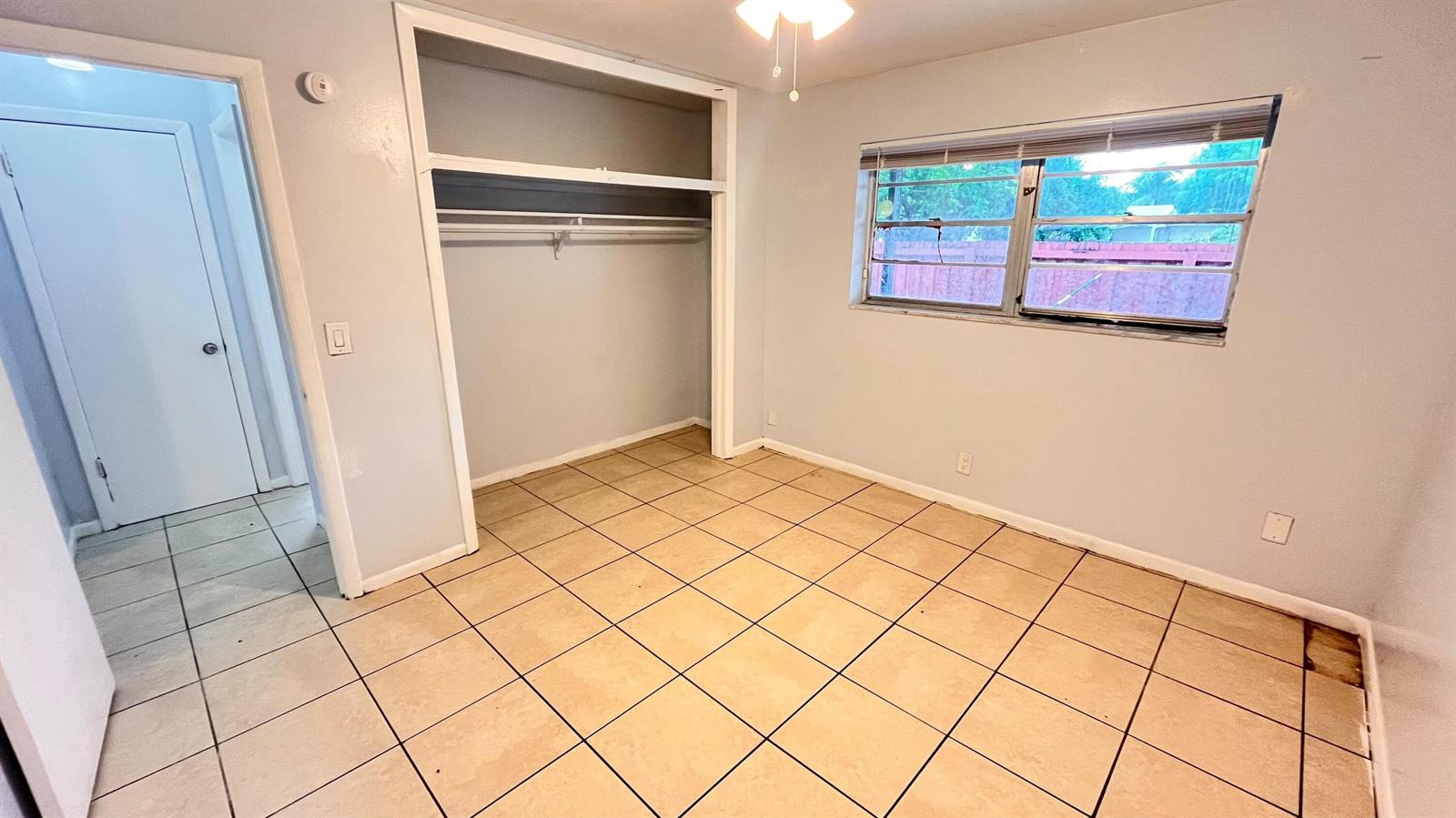 An empty bedroom features light-colored walls, a closet, a window, and tiled flooring — 919 S G Street, FL 33460, FL