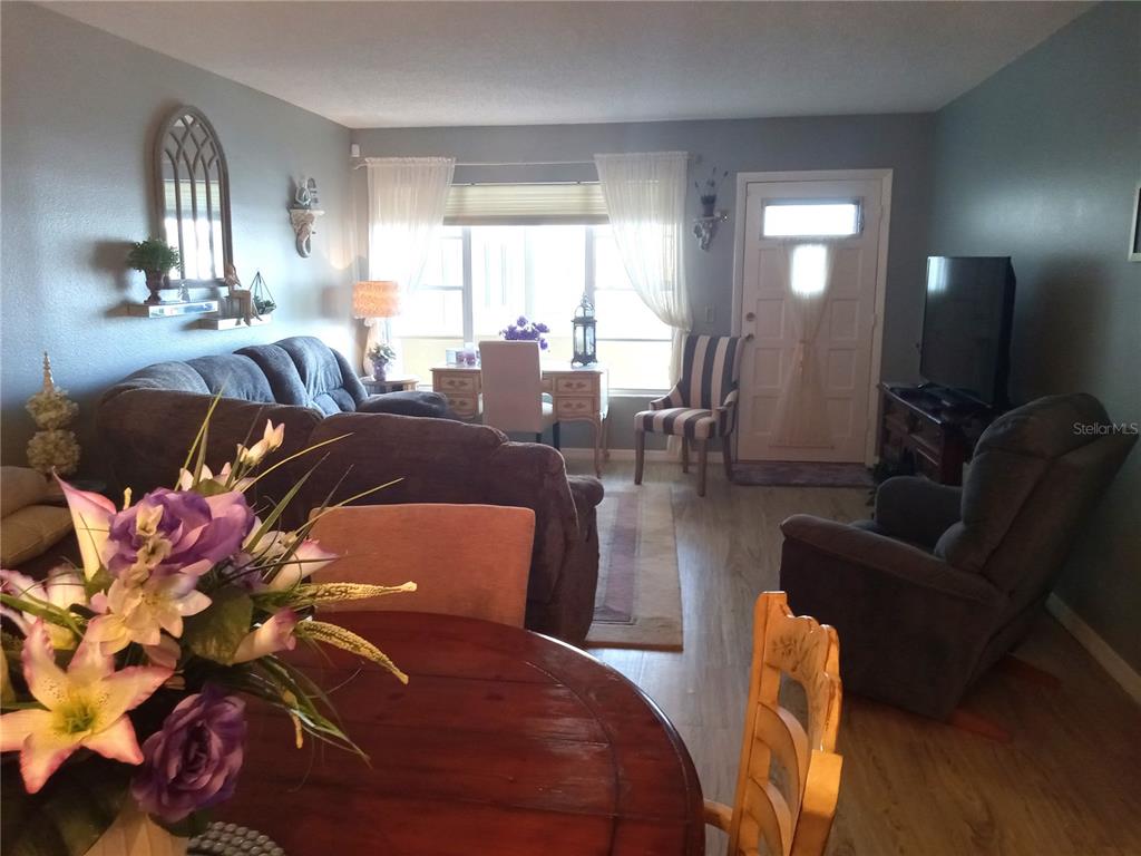 A living room features a dark sofa, a recliner, a dining table, and a front door — 2459 FRANCISCAN DRIVE UNIT 37, CLEARWATER, FL