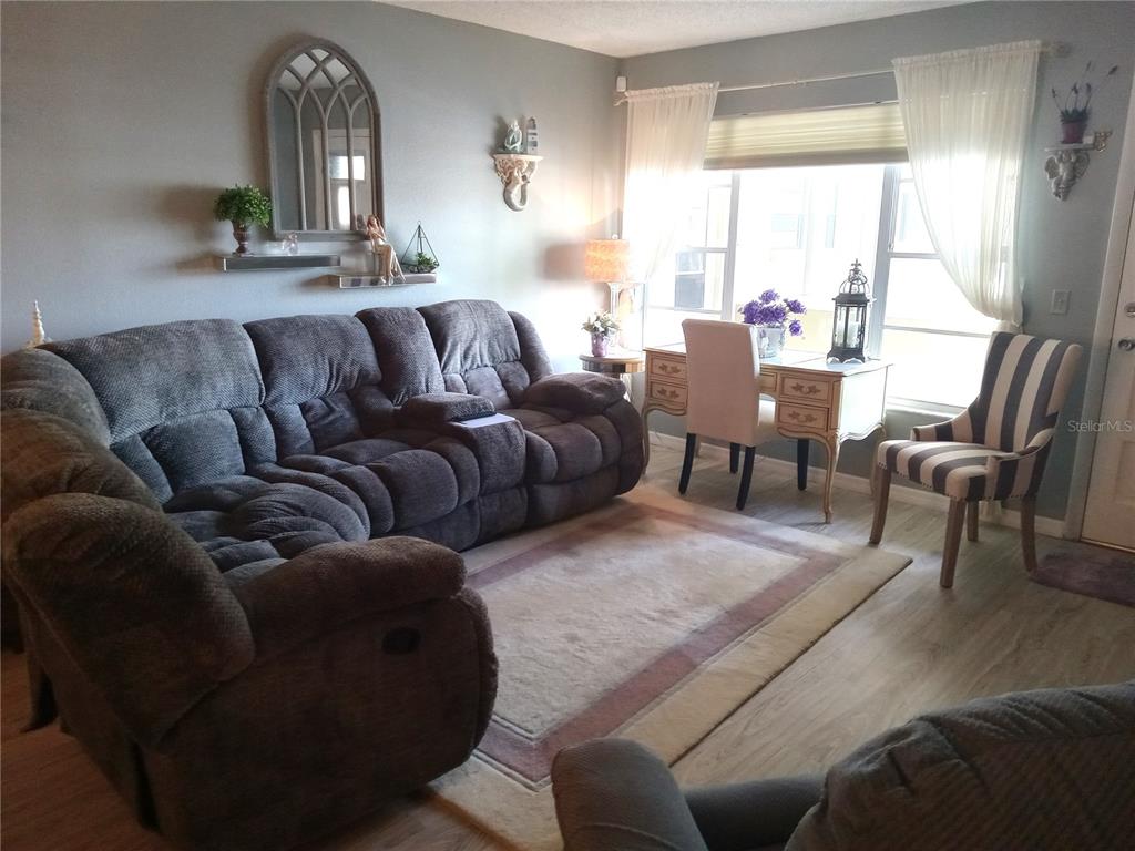 A living room features a large gray sectional sofa, a desk, and a striped chair — 2459 FRANCISCAN DRIVE UNIT 37, CLEARWATER, FL
