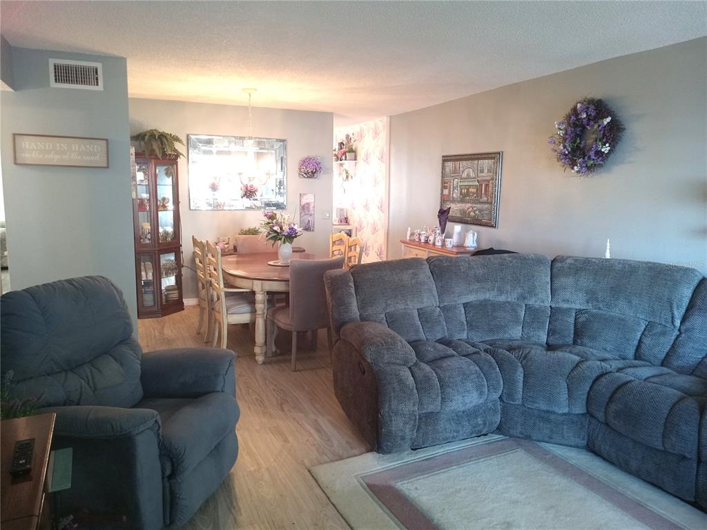 A living room with a gray sectional sofa, a recliner, and an adjacent dining area — 2459 FRANCISCAN DRIVE UNIT 37, CLEARWATER, FL