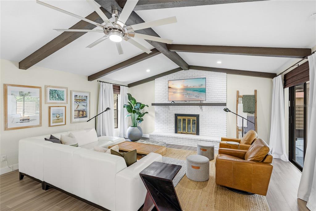A living room features a white sectional sofa, leather armchairs, a fireplace, and exposed beams — 6513 29TH AVENUE W, BRADENTON, FL