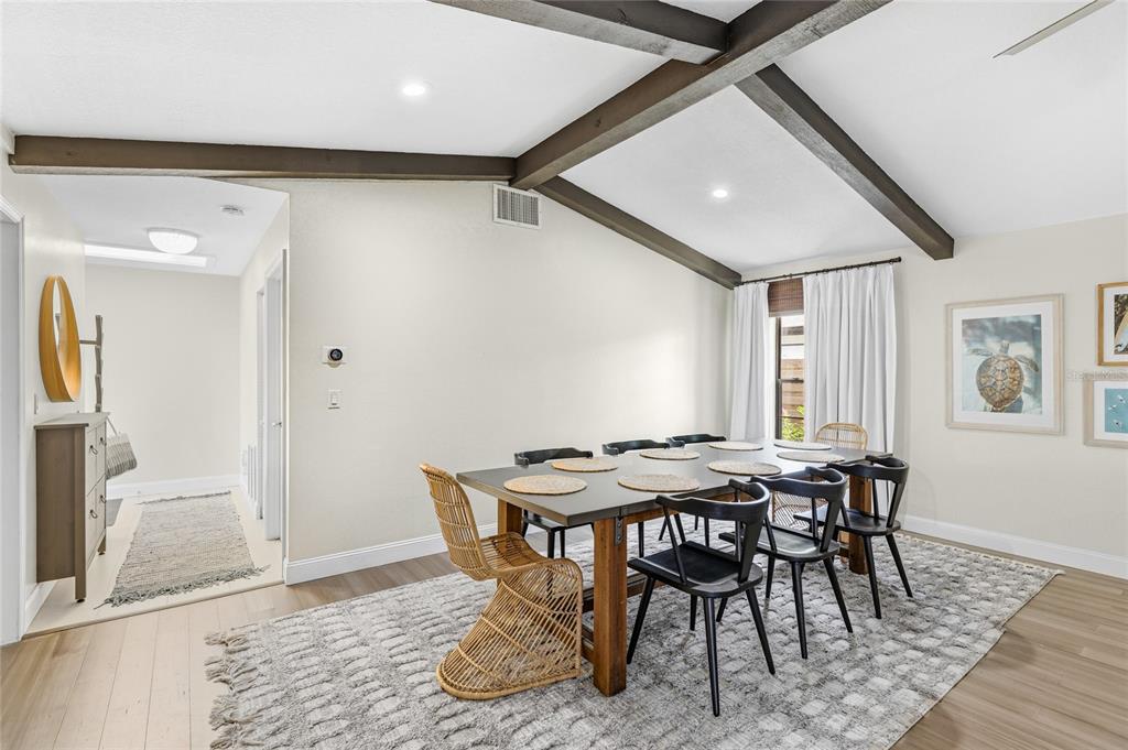 A dining room features a dark wood table, mixed seating, and exposed ceiling beams — 6513 29TH AVENUE W, BRADENTON, FL