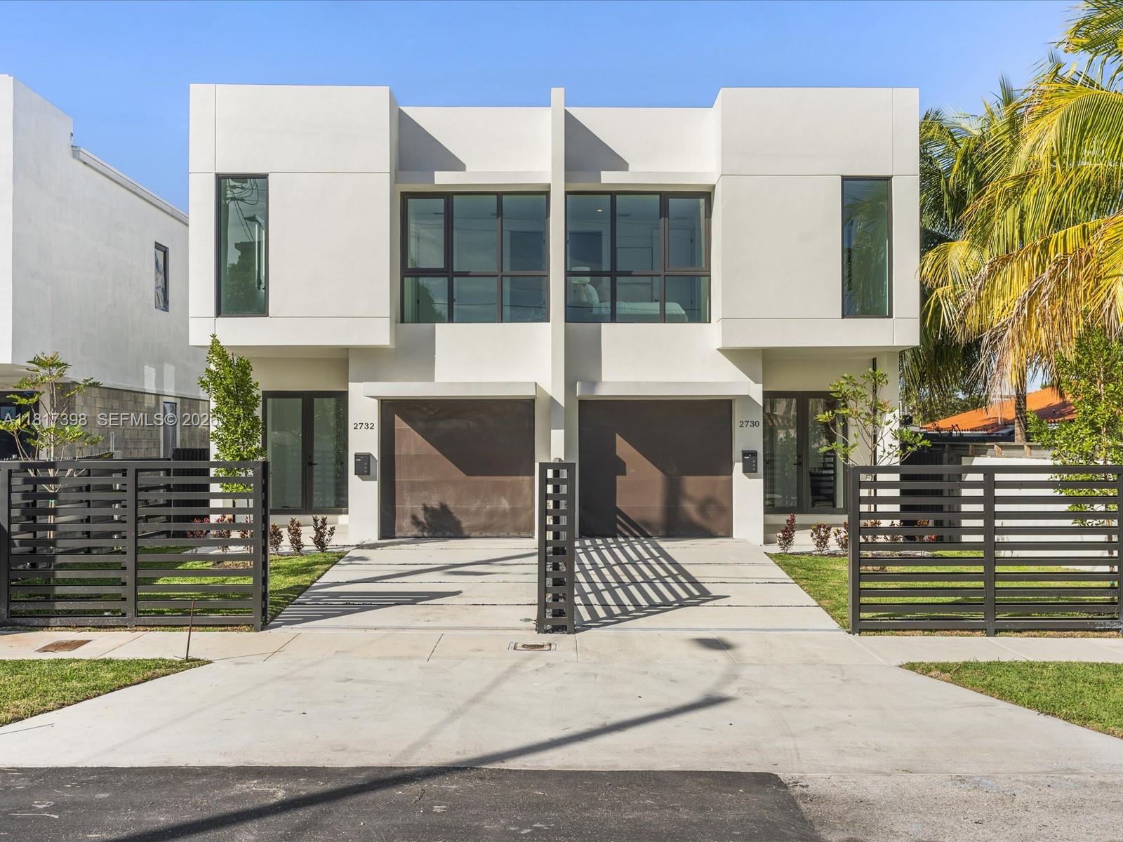 A modern two-story duplex features white exterior walls, dark garage doors, and black metal fencing — 2732 SW 31st Ave, Miami FL 33133, MIAMI, FL
