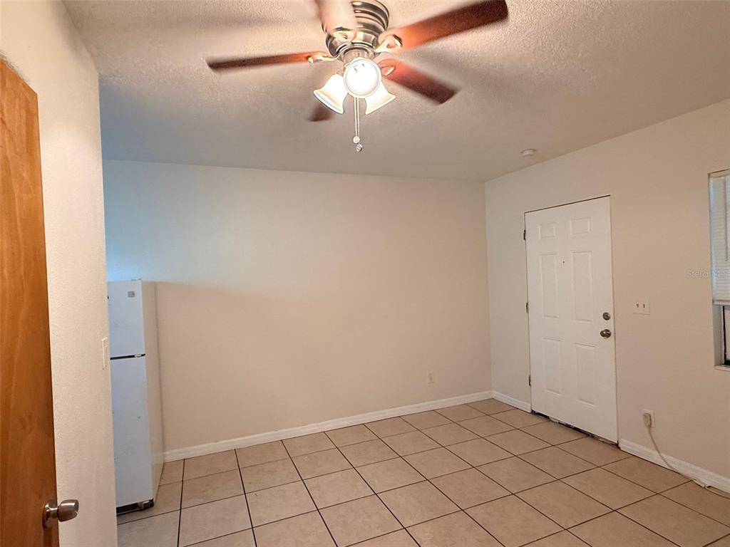 A room with beige tile flooring, a ceiling fan, and a white refrigerator — 2404 10TH STREET W UNIT 4, BRADENTON, FL