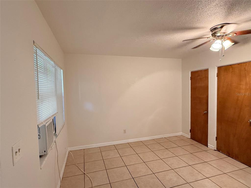 An interior room features light-colored walls, tiled flooring, a ceiling fan, and two wooden doors — 2404 10TH STREET W UNIT 4, BRADENTON, FL