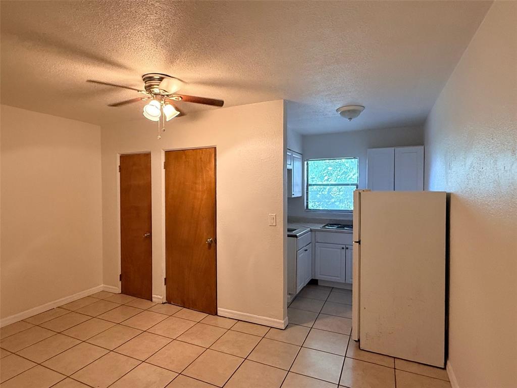 A kitchen with white cabinets and a refrigerator opens into a tiled dining area — 2404 10TH STREET W UNIT 4, BRADENTON, FL
