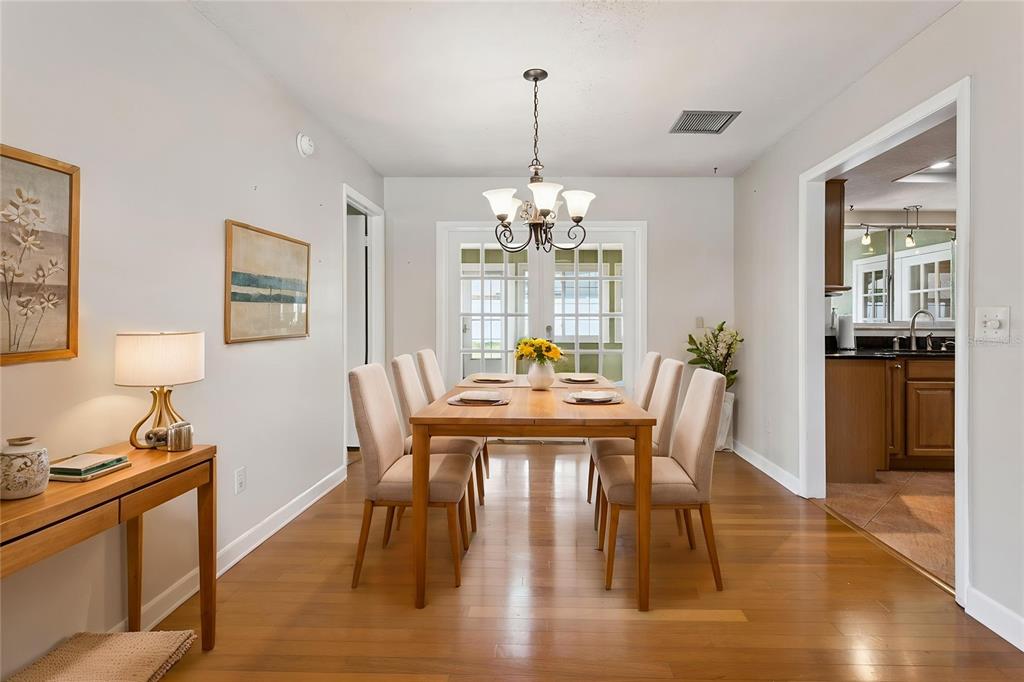 A dining room with a wooden table, six chairs, a chandelier, and hardwood flooring — 215 TWELVE LEAGUE CIRCLE, CASSELBERRY, FL