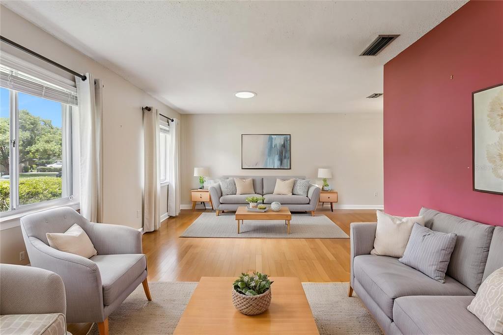 A living room features light wood floors, gray sofas, and a prominent red accent wall — 215 TWELVE LEAGUE CIRCLE, CASSELBERRY, FL