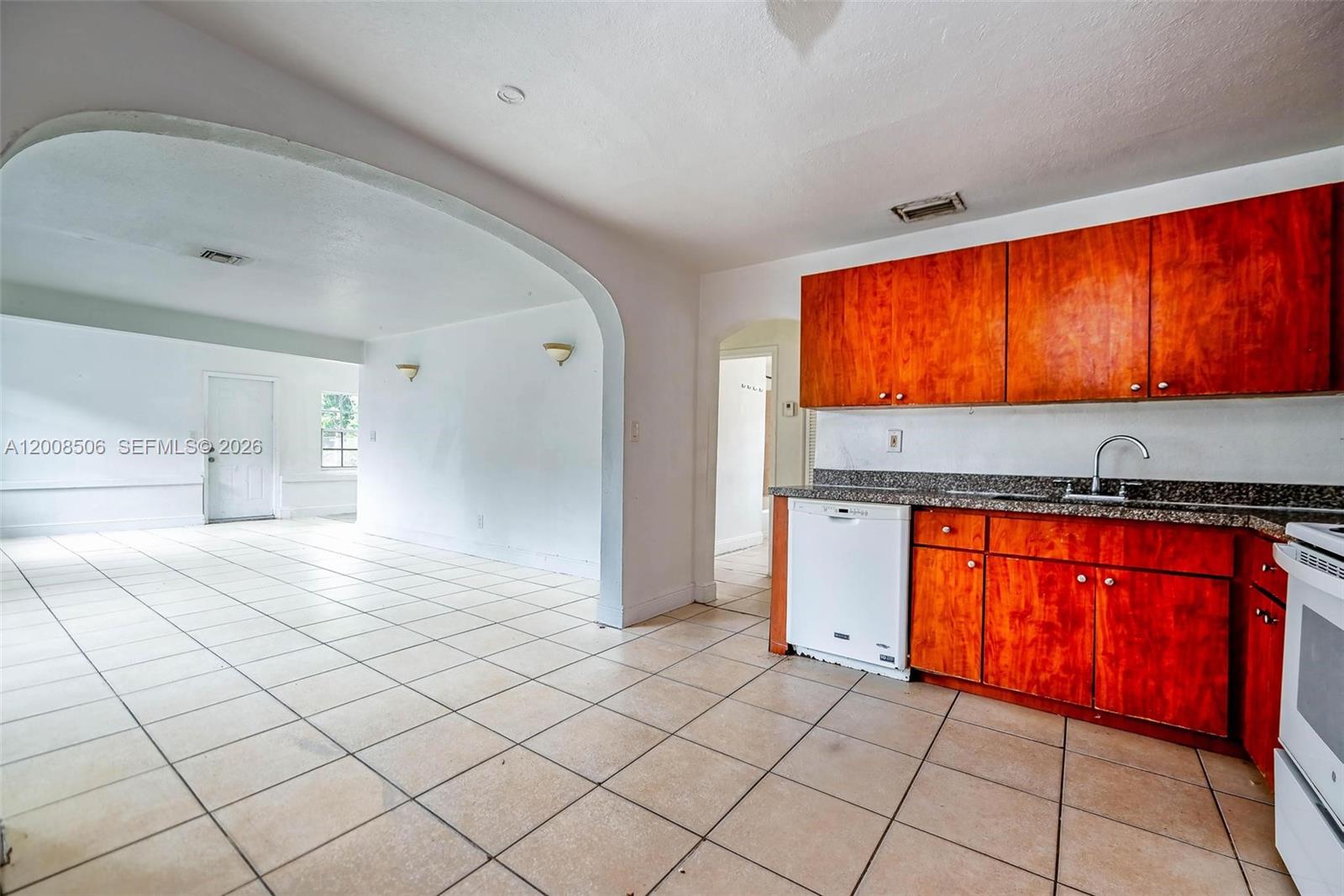 A kitchen with wood cabinets and a dishwasher opens into a large tiled living area — 2800 SW 16th Ter, Miami FL 33145, MIAMI, FL