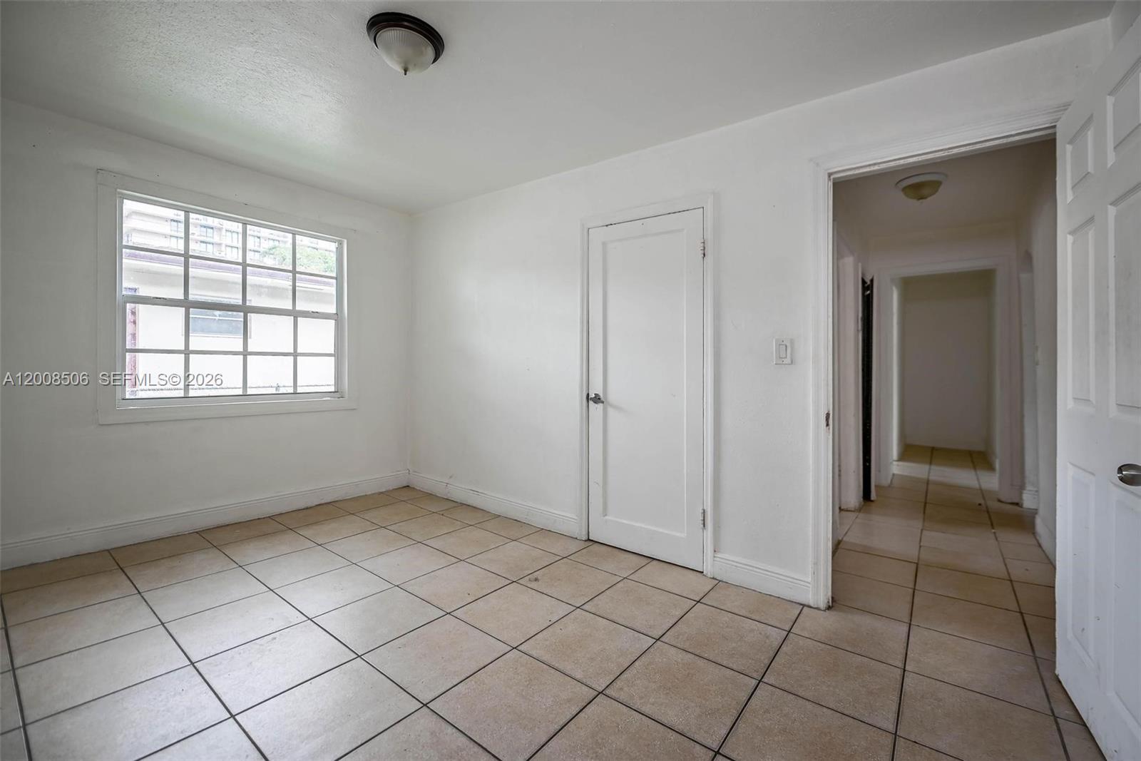 An empty room features white walls, a window, tiled flooring, and two interior doors — 2800 SW 16th Ter, Miami FL 33145, MIAMI, FL