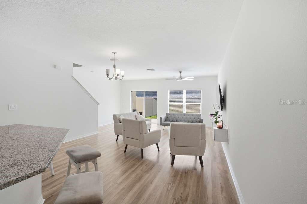 A living room with light wood floors, neutral furniture, and a granite-topped kitchen island — 9424 WESTSIDE HILLS DRIVE, DAVENPORT, FL