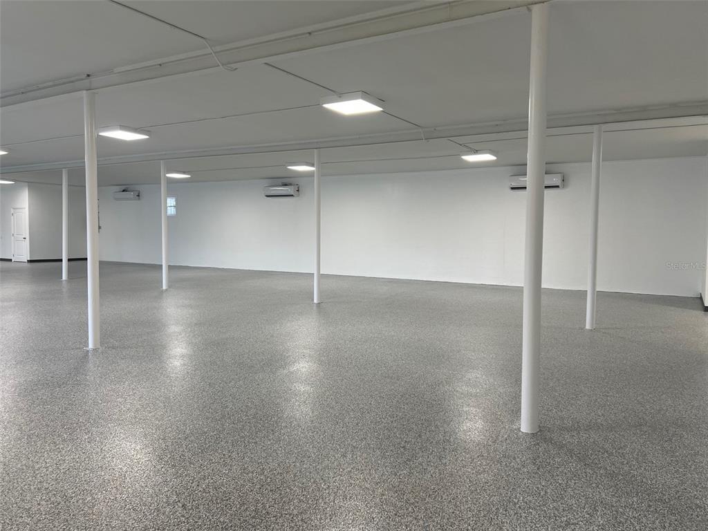 A large, open room features white walls, a speckled epoxy floor, and multiple support columns — 1710 N FORT HARRISON AVENUE, CLEARWATER, FL