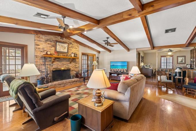 A living room features a brick fireplace, exposed wood ceiling beams, and hardwood flooring — 4925 HOPERITA STREET, ORLANDO, FL