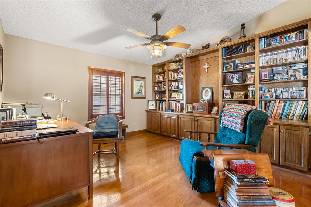 A home office with hardwood floors, a wooden desk, a recliner, and built-in bookshelves — 4925 HOPERITA STREET, ORLANDO, FL