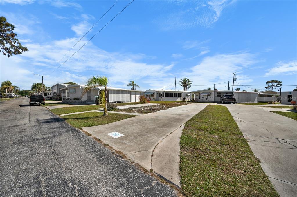 A street view of a mobile home park with concrete driveways and parked vehicles — 1891 ENGLEWOOD ROAD UNIT 107, ENGLEWOOD, FL