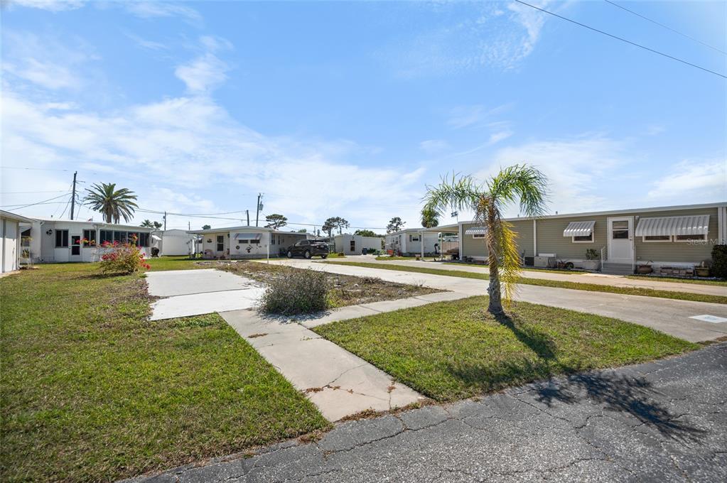 A view of a mobile home park with a vacant lot and a small palm tree — 1891 ENGLEWOOD ROAD UNIT 107, ENGLEWOOD, FL