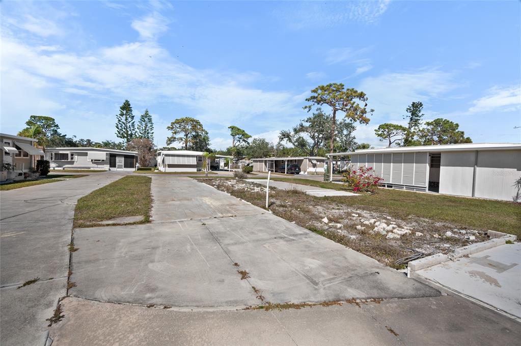 A concrete driveway leads to an empty lot in a mobile home community — 1891 ENGLEWOOD ROAD UNIT 107, ENGLEWOOD, FL
