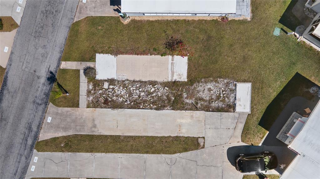 An aerial view shows a vacant residential lot with a concrete pad and scattered debris — 1891 ENGLEWOOD ROAD UNIT 107, ENGLEWOOD, FL