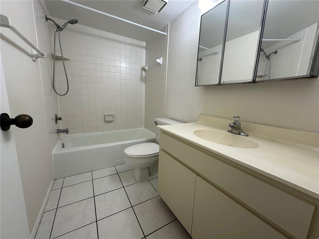 A bathroom features a tiled tub-shower combination, a white toilet, and a single-sink vanity — 7205 CURTISS AVENUE UNIT 2B, SARASOTA, FL