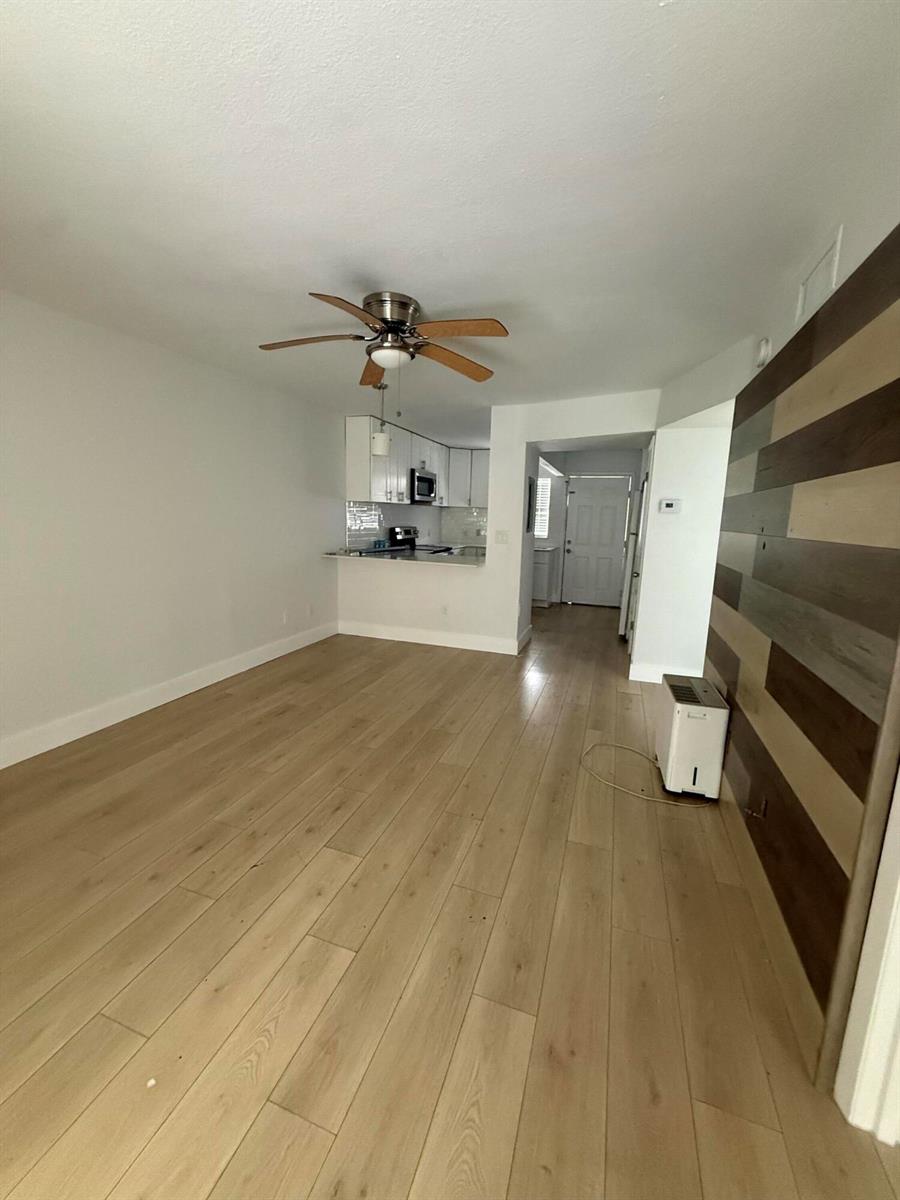 An open-concept living area features light wood flooring, a ceiling fan, and a kitchen pass-through — 605 Ixoria # 4, Fort Pierce FL 34982, FORT PIERCE, FL