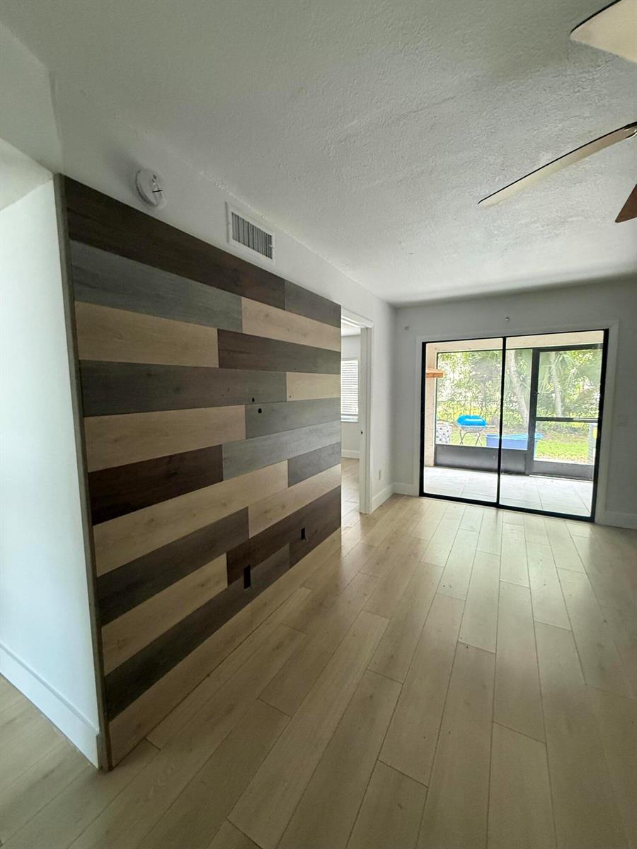 A room with light wood-look flooring and a multi-toned wood plank accent wall — 605 Ixoria # 4, Fort Pierce FL 34982, FORT PIERCE, FL