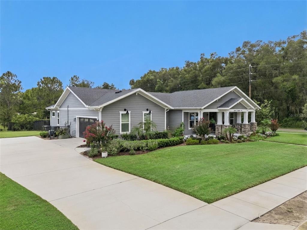 A gray, single-story house with a concrete driveway, front porch, and landscaped lawn — 491 W DELAWARE AVENUE, LAKE HELEN, FL