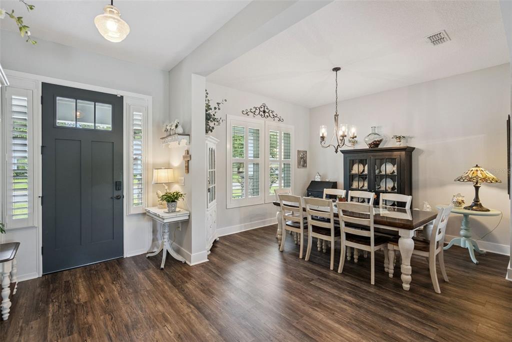A dining room with wood-look flooring, a dark front door, and a wooden dining set — 491 W DELAWARE AVENUE, LAKE HELEN, FL