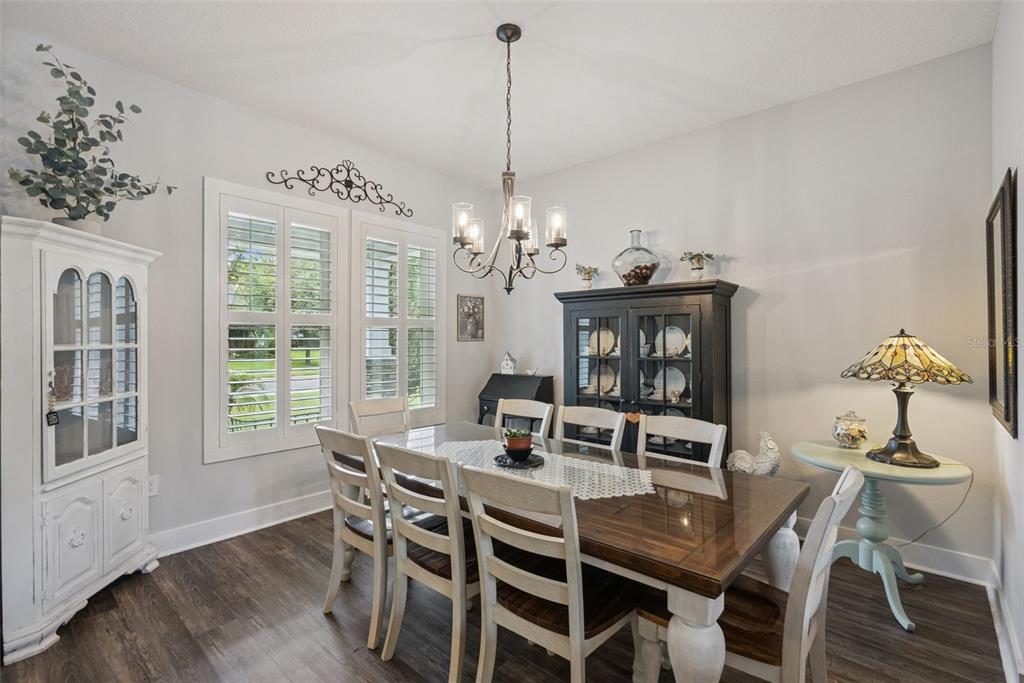 A dining room features a wooden table, six chairs, a chandelier, and two china cabinets — 491 W DELAWARE AVENUE, LAKE HELEN, FL