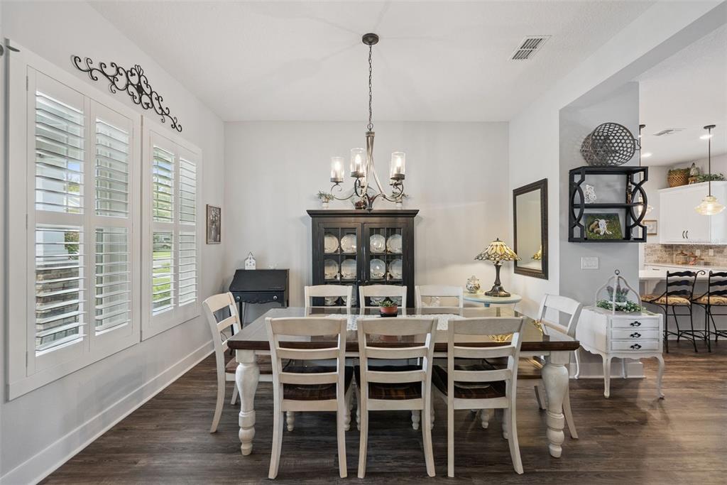 A dining room features a wooden table with white chairs, a black hutch, and shutters — 491 W DELAWARE AVENUE, LAKE HELEN, FL
