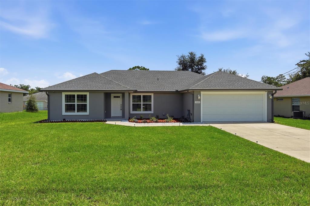 A single-story gray house with a two-car garage and a large front lawn — 15055 SE 93RD COURT, SUMMERFIELD, FL