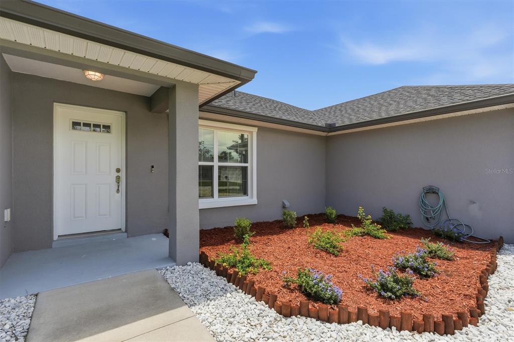 The exterior of a house features a white front door, gray siding, and landscaping — 15055 SE 93RD COURT, SUMMERFIELD, FL