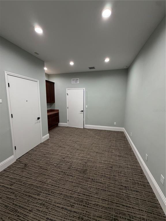A room with light green walls, patterned carpet, recessed lighting, and a small built-in cabinet — 5182 N OCEAN SHORE BOULEVARD UNIT A-3, PALM COAST, FL