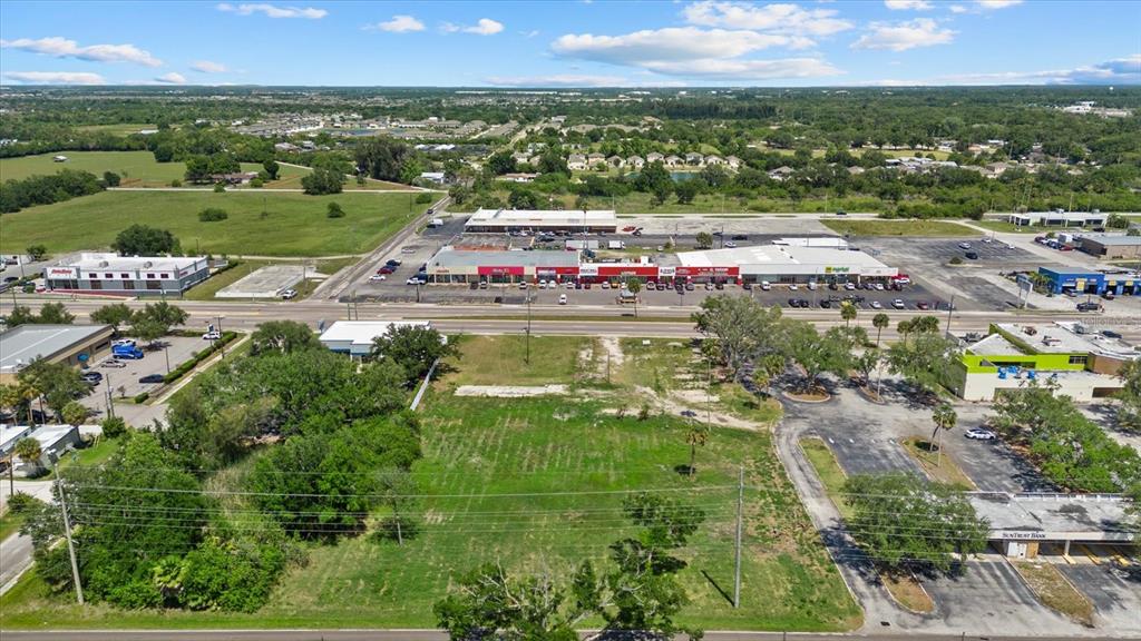 An aerial view shows a vacant, grassy lot situated between commercial buildings and parking areas — 610 N US HIGHWAY 41, RUSKIN, FL