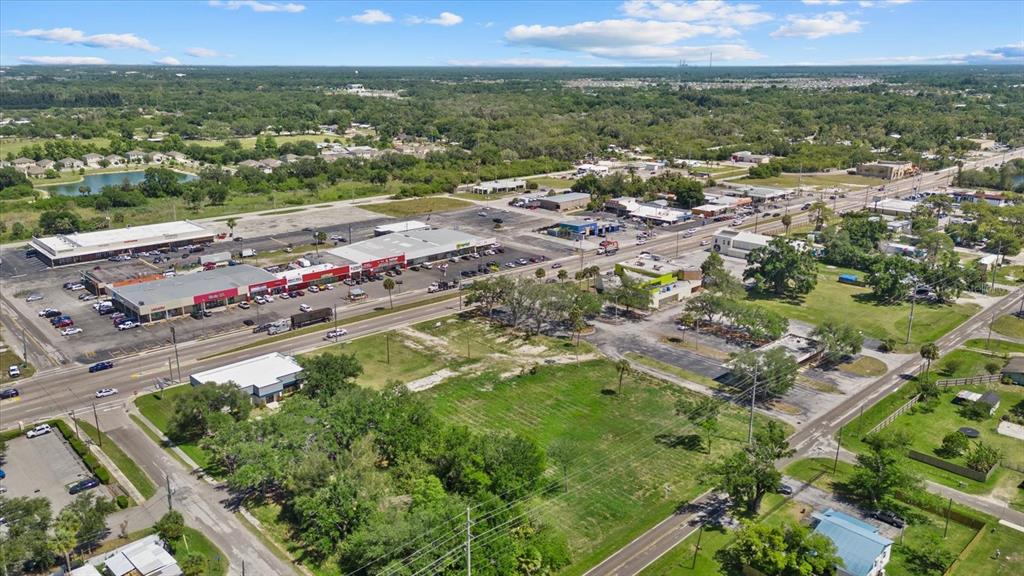 An aerial view shows a commercial strip mall, surrounding parking lots, and adjacent vacant land — 610 N US HIGHWAY 41, RUSKIN, FL