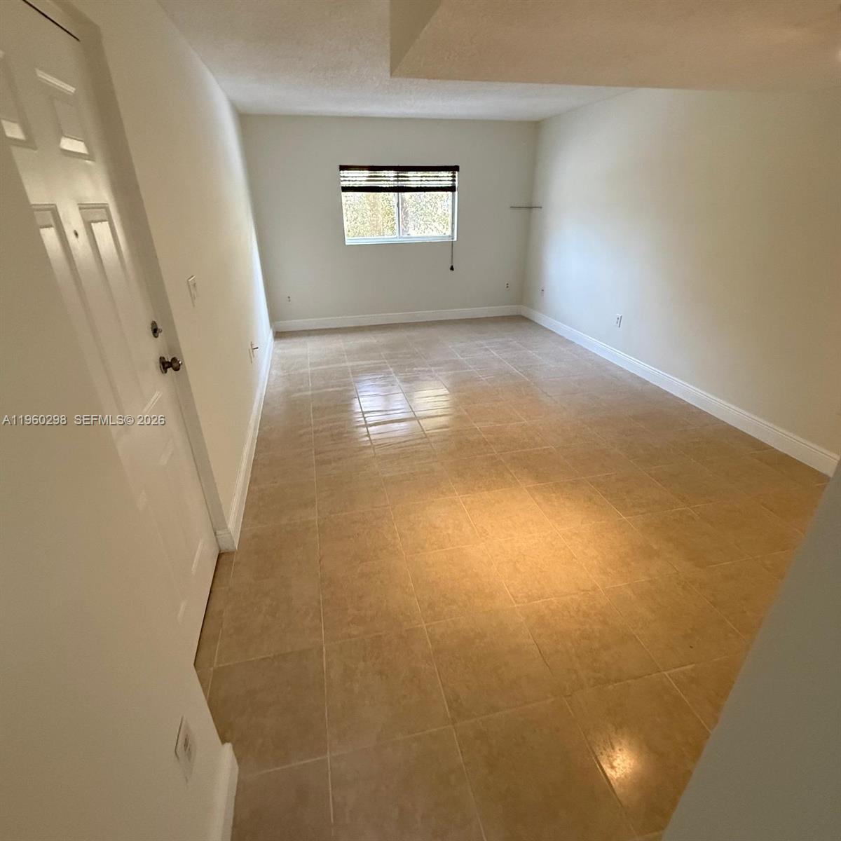 An empty room features beige tile flooring, white walls, and a single window — 8260 SW 149th Ct # 205, Miami FL 33193, MIAMI, FL