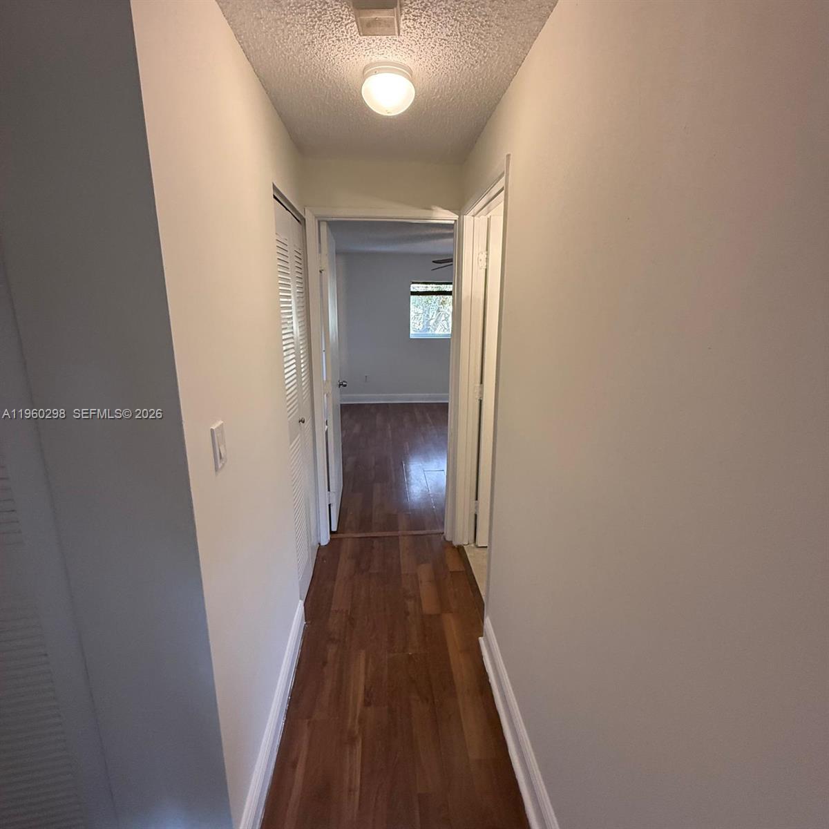 A narrow hallway with wood-look flooring leads to a bedroom with a window — 8260 SW 149th Ct # 205, Miami FL 33193, MIAMI, FL