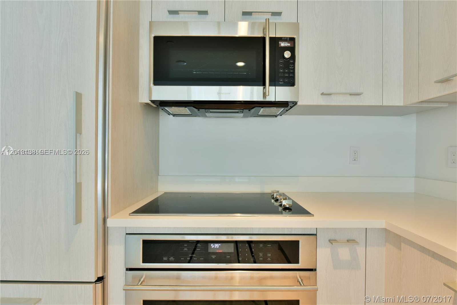 A modern kitchen features light wood cabinets, stainless steel appliances, and a glass cooktop — 45 SW 9 st # 1907, Miami FL 33130, MIAMI, FL