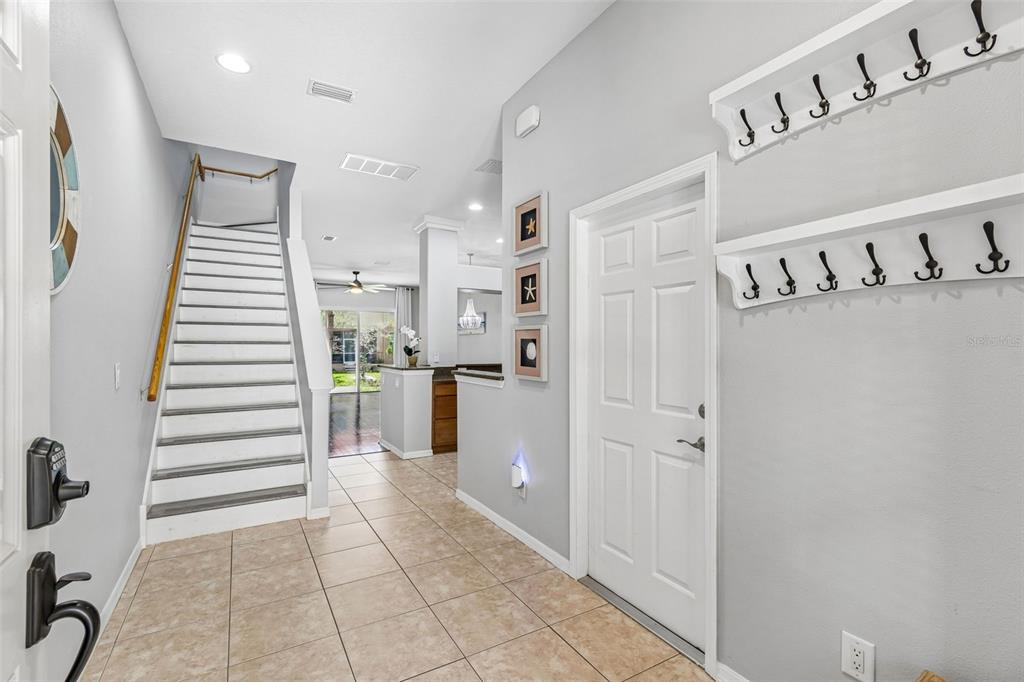 A tiled entryway features a staircase with a wooden handrail and wall-mounted coat racks — 1455 HIDDEN COURT, TARPON SPRINGS, FL