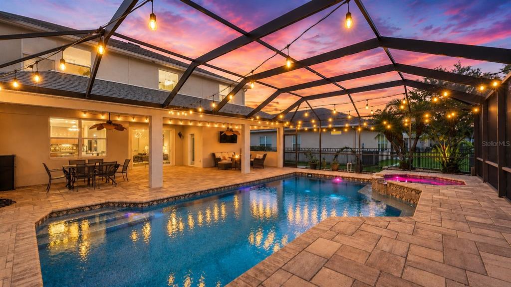A screened-in patio features a swimming pool, hot tub, and outdoor dining area at sunset — 8839 39TH STREET CIRCLE E, PARRISH, FL