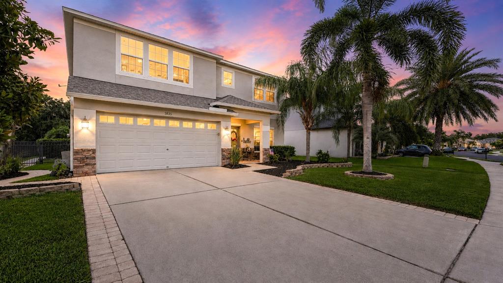 A two-story suburban house with a concrete driveway, a two-car garage, and palm trees — 8839 39TH STREET CIRCLE E, PARRISH, FL