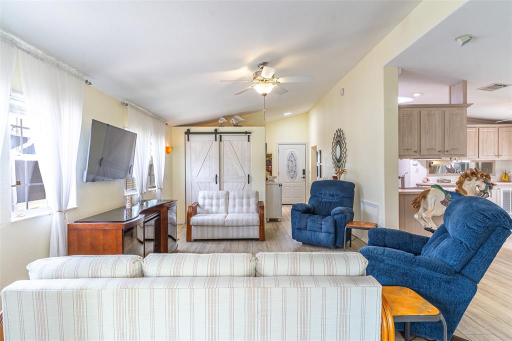 A living room features a vaulted ceiling, light-colored walls, wood-look flooring, and blue recliners — 511 PAR PINES BOULEVARD, DAVENPORT, FL